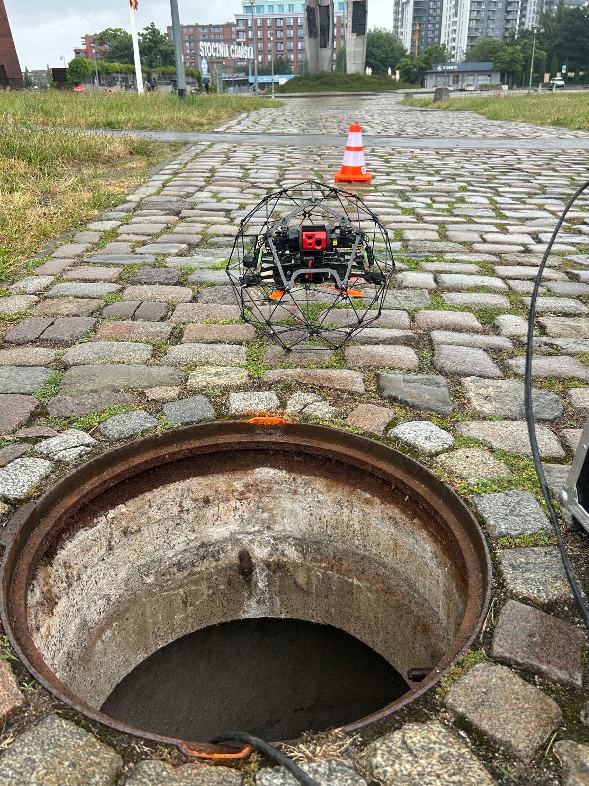 Dron Flyability Elios 2 w klatce ochronnej nad studzienką